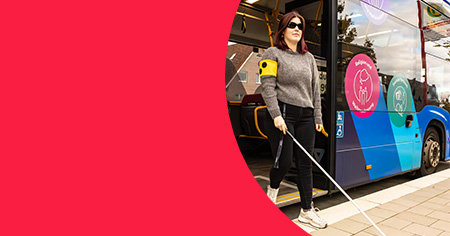 Frau steigt mit Langstock aus Bus aus